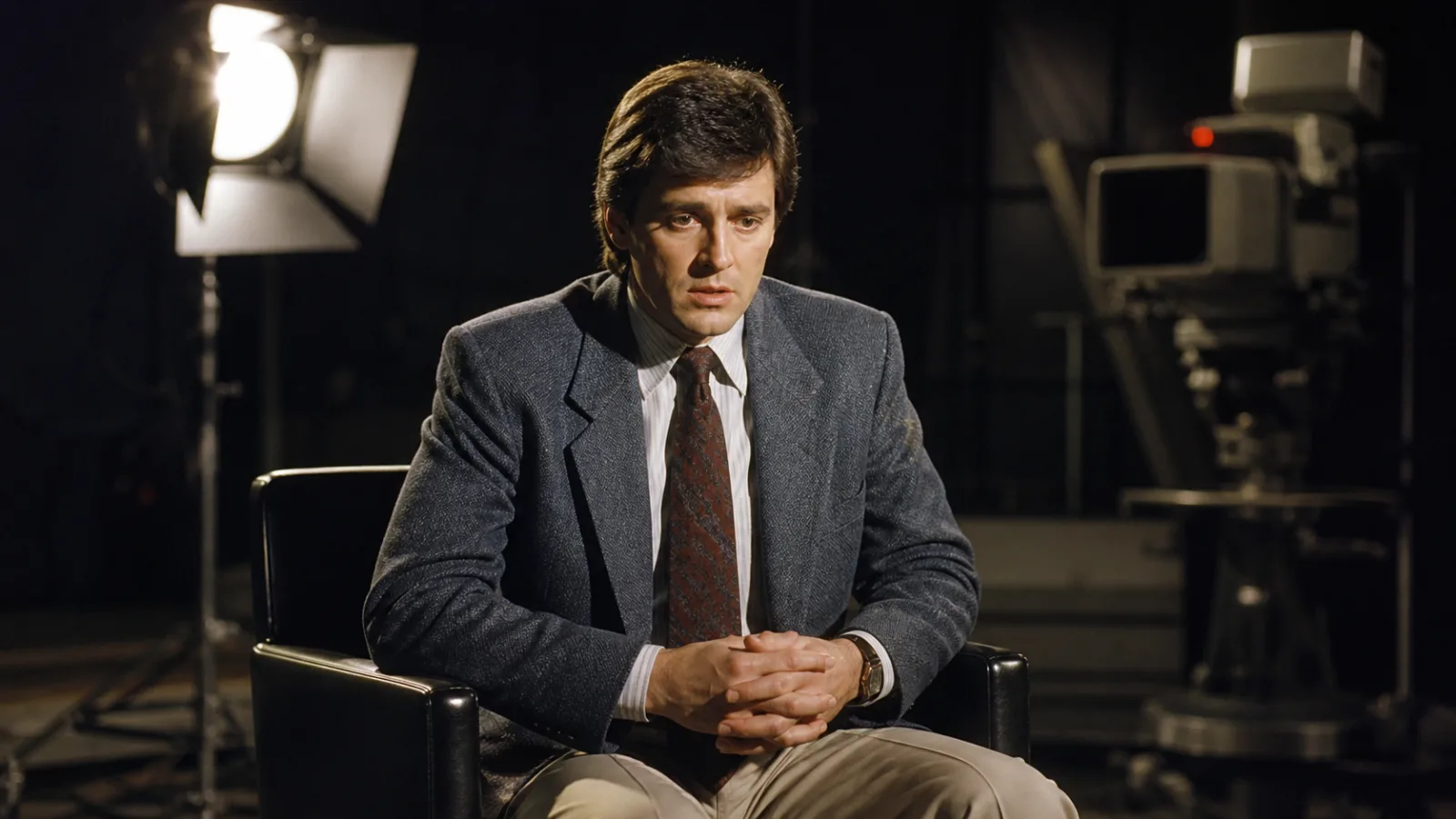 Reenactment of a man under bright television studio lights preparing for a 1980s interview about secret government technology